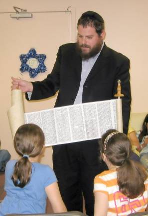 Rabbi Pesach Burston shows Hebrew School students the inside of a Torah scroll.