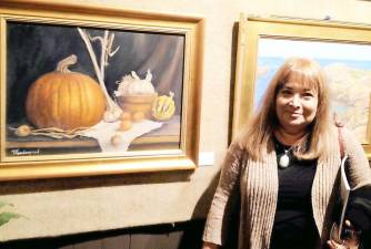 Artist Marylyn Vanderpool standing next to her fall themed painting.