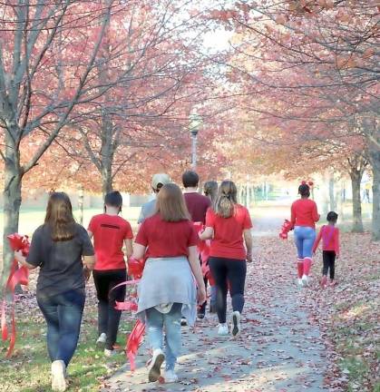 Students walk to tie Red Ribbons to trees at the Orange County Government Center in Goshen.