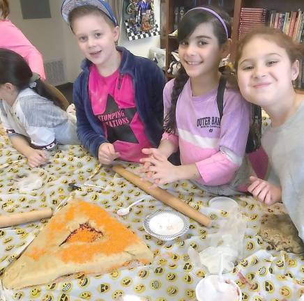 Owen Leonard of Washingtonville, Morgan Reich of Highland Mills and Ava Lejovitzky-Reich of Harriman make a giant hamantash at Chabad.
