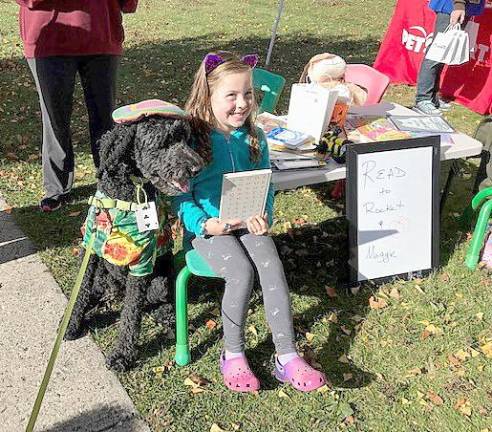 During the Monroe Free Library's Spooky Pooches Howl-O-Ween event, library staffers set up a table so that children could read to Rocket, the library therapy dog. The staff also had an ink pad so that Rocket could paw print autograph the book that the children read to him and bring it home as a souvenir.