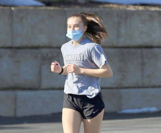 There is a smile behind that mask: Members of the Monroe-Woodbury Girls Cross Country team took advantage of the warm weather to get ready for its season.