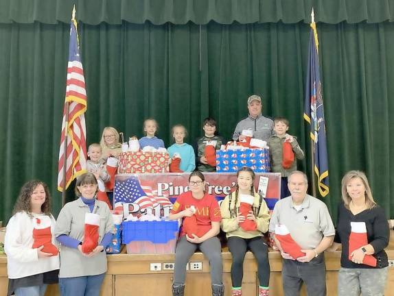 Members of the Patriot Club, family members and Pine Tree Principal Bryan Giudice stuff stockings for troops this holiday season at their school in Monroe.