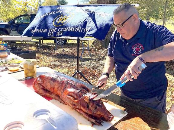 Donnie Prozzillo, a past chief of the Woodbury Fire Department, begins to carve a roasted pig for the anniversary barbecue.