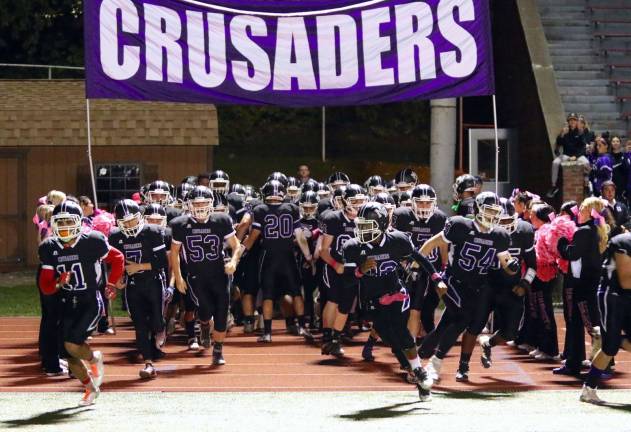 Photos by William DimmitThe Crusaders storm on to the field to start the game.