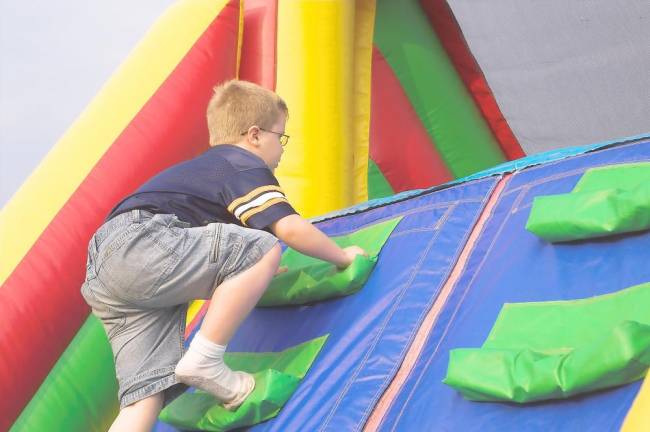 A boy does some climbing in an inflatable park. The Castle will have 12 activity areas, including a Ninja Wall for climbing.