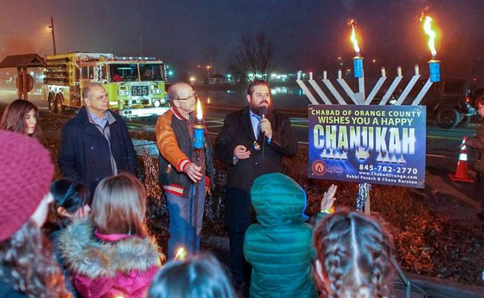 At the Monroe Menorah Lighting on the first night of Hanukkah following the Gelt Drop: Pictured from left to right are: Chana Burston, Monroe Town Supervisor Tony Cardone, Monroe Village Mayor Neil Dwyer and Rabbi Pesach Burston.