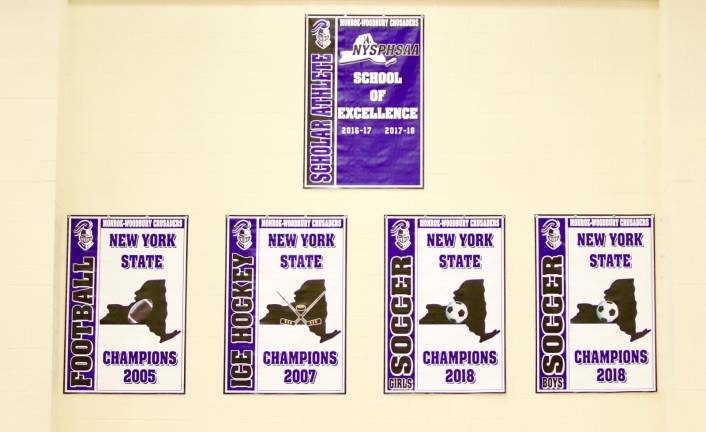 The NYSPHSAA Scholar Athlete School of Excellence and four State Championship banners hang on wall on the south wall of the Monroe-Woodbury High School gym.