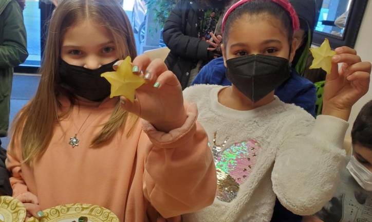Ainsley Rogers of Middletown and Arianna Briggins of New Windsor learn how to recite the “Shehechiyanu” blessing upon tasting a “new fruit.”