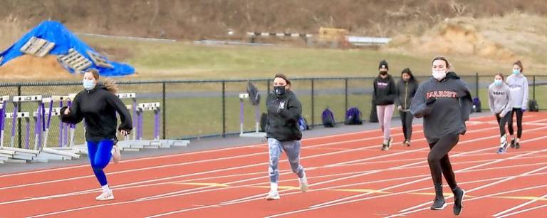 Girls from the track team are masked up as they begin their work outs in the cold January air.