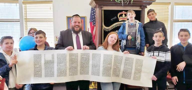 Rabbi Pesach Burston shows an authentic “Megilllah Scroll” to his class at Chabad Hebrew School. The Megillah is a hand-written parchment scroll which is read on Purim, telling the story of the holiday.