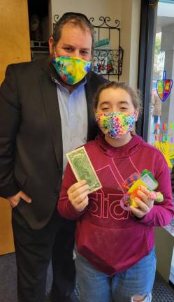 Rabbi Pesach gifts Chabad Hebrew School student Alana Schrank of Goshen with a two-dollar bill of Chanukah Gelt (money) and Chanukah goodies in celebration of the holiday.