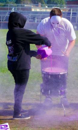 A masked drummer preforms with the drumline.