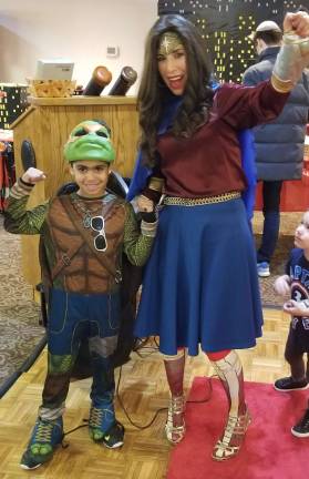 Chana Burston awards Ilay Tsabari, 8, of Monroe, with a prize at Chabad of Orange County’s Superhero Purim Party’s masquerade.