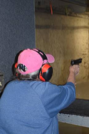 An older woman tries out a firearm at Master Class Shooters Supply in Monroe, N.Y. (Photo by Rose Miller)