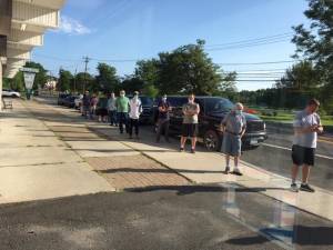 Worth the wait: about a dozen patrons line up, six feet apart, outside Vincenzo’s Barber Shop.