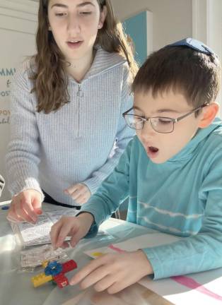 Hudson Mendelovitz, of Central Valley, is fascinated by the dreidel he made at Chabad Hebrew School. Also pictured is his teacher, Shira Rimler. Hudson’s family is hosting Chabad’s Central Valley Menorah lighting on Monday, December 19.