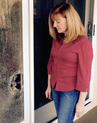 Photos provided Warwick resident Patricia Tripken again inspects the damage done to her home from a bullet which police suspect came from a hunter's firearm.
