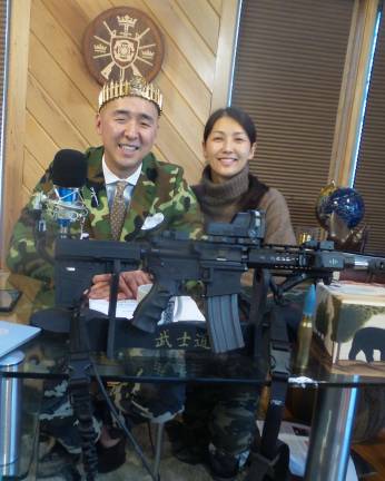 Hyung Jin Moon (Sean Moon), pictured with a crown of bullets, with his wife, Yeon Ah Lee Moon, and an AR-15 (Photo by Frances Ruth Harris)