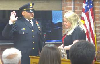 Woodbury Town Clerk Desiree Potvin administers the oath of office to Michael Faravashi of the Woodbury Police Department, who was promoted to the position of sergeant.