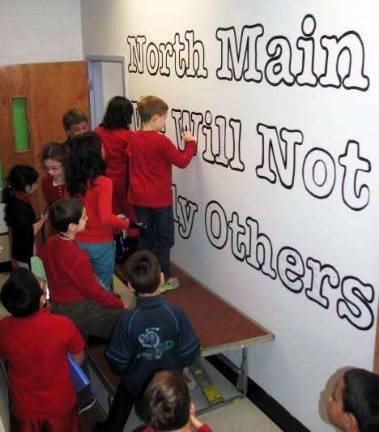 Photo by Nancy Kriz Students from Kristin Haas&#xed; third-grade class sign their names to North Main&#xed;s anti-bullying wall, featuring the first rule of the Olweus bullying prevention program, &#xec;We will not bully others.&#xee;