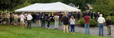 People gathered under the tent and along the lawn to observe the remembrance service.