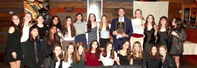 Head Coach Christopher Goodwin holds his cross-country Coach of the Year award with his team.