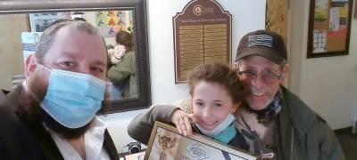 From Generation to Generation: Rabbi Pesach Burston hands Alan Friedman of Pine Bush and his granddaughter, Sofia, of Goshen, a box of Passover Shmurah Matzah. The Passover Seder is centered around the theme of “telling your children” about the Exodus and inspiring the traditions from generation to generation.