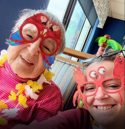 A resident poses with staff during a Hawaiian luau celebration at Belle Reve.