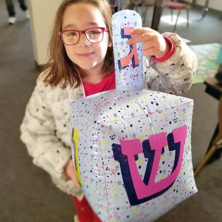 Hebrew School student Libby Einav of Monroe plays with a giant dreidel.