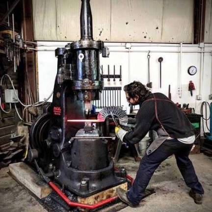 Patrick Quinn, CMA forging studio coordinator, forging parts for a sculpture with a power hammer.