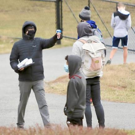 Matthew Hemmer, assistant coach of the Boys Varsity Cross County team, checks athletes temperature before they are able to start practice. Photos by William Dimmit.