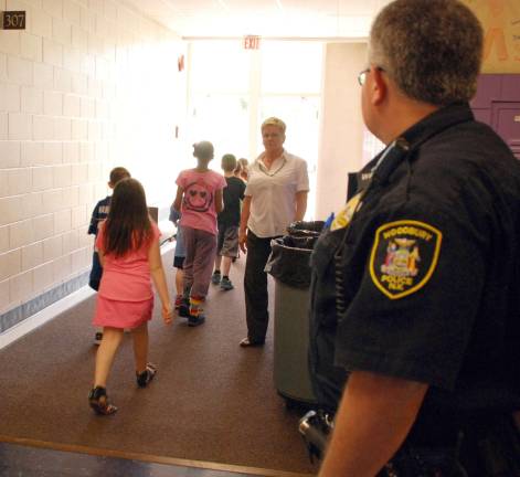 Under the watchful eye of a Town of Woodbury Police officer, students evacuate Central Valley Elementary School last Tuesday as part of a planned drilled.
