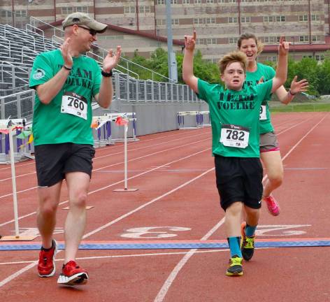 Andrew Voelke raises his arms at the finish line after defeating the tough 5k course.