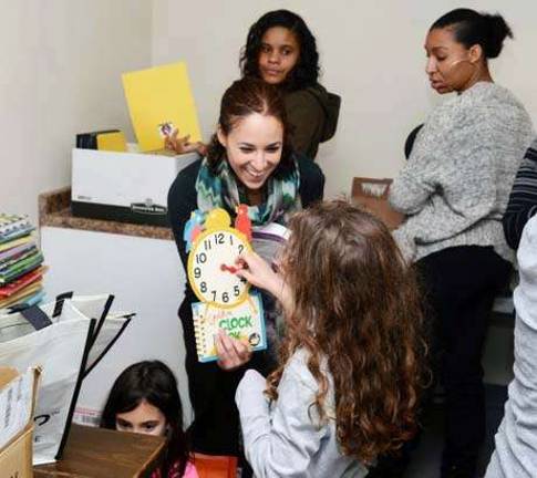 Brownie Girl Scout Sara Labrada passes the books down the assembly line from Annie Labrada to Yasmine Kalkstein to help back over 200 care packages that included educational materials and other goodies. The Jewish Federation of Newburgh donated the space to store and pack.