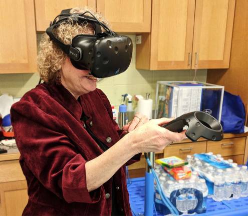 That’s Marilyn McIntosh, executive director of the Monroe Free Library, behind the headset and holding the controls that operate the virtual reality programs.