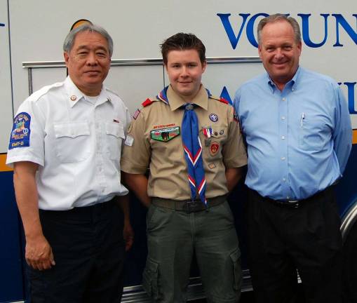 Photo by Scott Berger An &igrave;Eagle Scout Court of Honor&icirc; was held June 9 at the Monroe Volunteer Ambulance building for William Paul Boese, whose project was constructing an outdoor patio, seating and planting area for the building. The work was completed in October 2010. William is pictured here flanked by Wayne Chan, past president of the Ambulance Corps, on his left, and Greg Townsend, a trustee of the Ambulance Corps on his right.