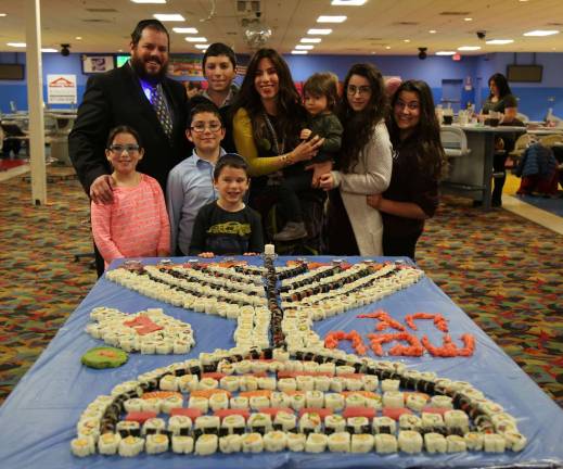 Rabbi Pesach and Chana Burston, pictured with their children and some staff, at last year&#x2019;s Sushi Menorah in Chester. This year, it will be a Military Mitzvah Menorah community party on Dec. 13 at Colonial Lanes in Chester.