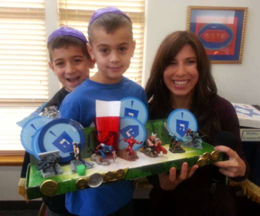 Tom and Ethan Einav, of Highland Mills, pictured with Chana Burston, at a previous Menorah Contest. Chabad this year is again holding a community-wide Menorah Contest.