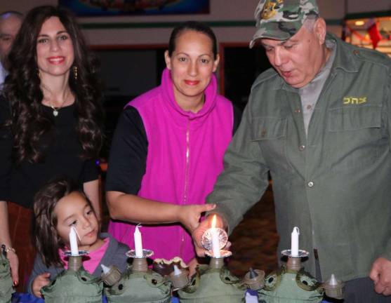 Candle for the IDF: Lighting the first candle of the Mitzvah Military Menorah, honoring the Israel Defense Force, are IDF veterans Limor Einav of Highland Mills and Eli Ram of Monroe.
