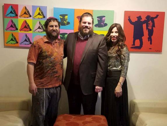 Photos Courtesy of Rabbi Pesach and Chana Burston &quot;Pop Art Rabbi&quot; Yitzchok Moully, pictured with Chabad Rabbi Pesach and Chana Burston in front of Moully's pop art hanging in Chabad's lobby, led a Jewish Pop Art event at Chabad.