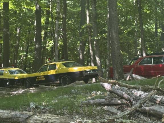 Vintage-looking cars, some outfitted to appear as old “New York State Police” vehicles, on-set in Harriman.