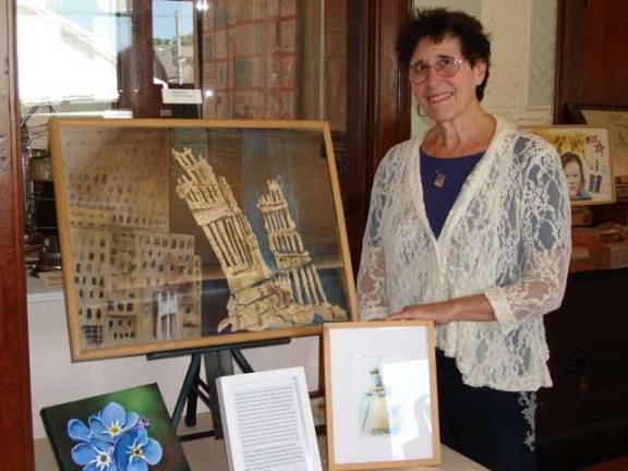 Artist Karen E. Gersch with &#x201c;Skeletal City,&#x201d; a mixed media work depicting the destruction of the Twin Towers on September 11, 2001. Other artwork on the table in front of her includes a print of &#x201c;We Have Lost,&#x201d; her first 911 painting. (Photo by Geri Corey)