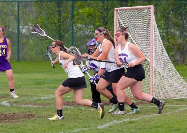 Photo by William Dimmit Swarming defense: Andrea Hill (#4), Erica Doering (#28) and Anna Delaney (#21) rush to block a shot from reaching Goalie Corinne Buttner in Monroe-Woodbury's 13 to 2 victory over Warwick Valley on May 2. Delaney is this week's Monroe-Woodbury High School "Athlete of the Week."
