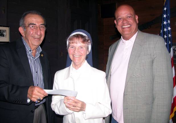 Garden of the Child founder Sister Anna Roche accepts the organization&iacute;s 23nd annual contribution from the Warwick Valley Rotary Club. Leo Kaytes, left, helped promote the start-up efforts in 1989 when he was Rotary president. Since then Warwick Rotarians have donated almost $25,000 to Garden of the Child. At right is Wayne Patterson, Rotary Warwick Rotary president. Photo by Stan Martin