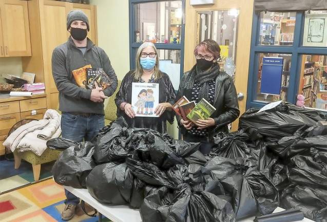 Matt Gonzalez, Melissa Quarles and Shanna Sussens in front of bags of book donations at the Monroe Free Library.