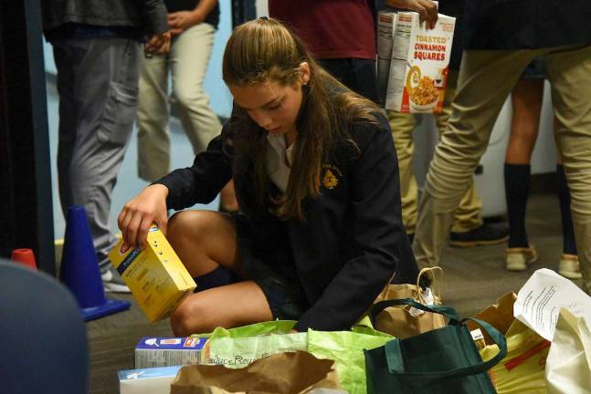 Photo by Christopher Kasker, Tuxedo Park School Tuxedo Park School eighth-grader Ally Turner of Warwick sorts through food items at George Grant Mason School in Tuxedo. Tuxedo Park School families donated the items as a community service project to support the Tuxedo School District’s BackPack program.