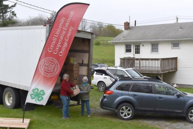 CCE Orange County Agriculture Program Leader Maire Ullrich at the Orange County Vegetable Growers Research Center helps Carol Roe of Roe’s Orchard in Chester load the hand sanitizer.