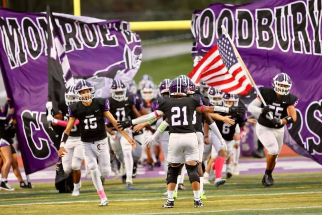 The Crusaders crash through the banner and take the field under the lights.