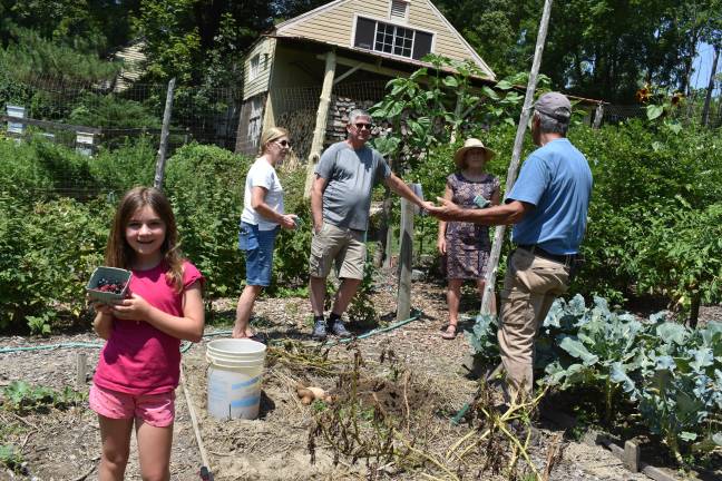 Larry Mansour talks potatoes with visitors to his Warwick, N.Y., garden while a young visitor shows off her berry haul. (Photo by Becca Tucker)